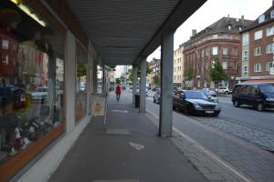 an empty sidewalk next to a street with parked cars at Ferienwohnung Georgstrasse in Bremerhaven