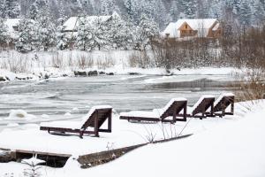 una fila de bancos cubiertos de nieve junto a un río en KLEN Family, en Mykulychyn