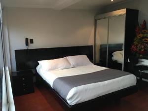 a bedroom with a large bed with a black headboard at Hotel Ejecutivo Embajada in Bogotá