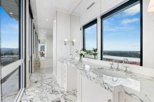 une salle de bains blanche avec deux lavabos et une grande fenêtre dans l'établissement Swainson at M1, à Adélaïde