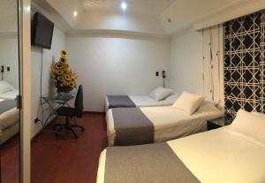 a hotel room with two beds and a television at Hotel Ejecutivo Embajada in Bogotá