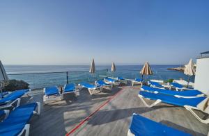 a deck with chairs and umbrellas and the ocean at Hotel Balcón de Europa in Nerja