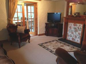 a living room with a flat screen tv and chairs at Berwick Hall Cottage in Moira