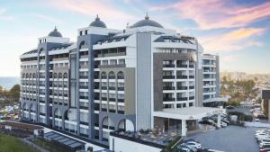 ein großes weißes Gebäude mit Parkplatz in der Unterkunft Alarcha Hotels & Resort - Ultra All Inc in Manavgat