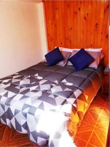 a bedroom with a large bed with blue pillows at Cabaña Isla Negra in Isla Negra