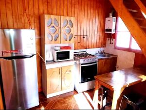 a kitchen with a stove and a refrigerator and a table at Cabaña Isla Negra in Isla Negra