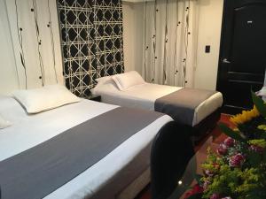 two beds in a hotel room with flowers at Hotel Ejecutivo Embajada in Bogotá