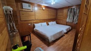 una camera da letto con letto bianco in una camera in legno di 四重溪洺泉溫泉旅館 a Checheng