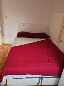 uma cama com um cobertor vermelho em cima em Empire Apartments em Skopje