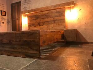 uma cama de madeira num quarto ao lado de uma parede em Relais La Font em Castelmagno