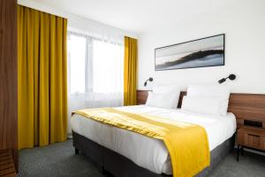 a hotel room with a large bed with yellow curtains at Hotel Vestina in Wisła