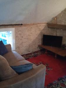 a living room with a couch and a desk with a laptop at Loft vintage avec cuisine intégrée in Pouilly-en-Auxois