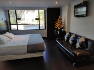 a bedroom with a bed and a couch and a television at Hotel Ejecutivo Av la Esperanza in Bogotá