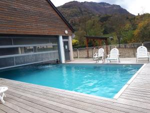 a swimming pool with chairs on a wooden deck at Appartement 2 chambres avec jardinet, piscine vue sur la montagne in Luz-Saint-Sauveur