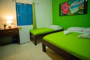 a green room with two beds and a desk at Alojamiento San Martín in San Andrés