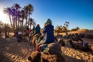 eine Gruppe von Menschen, die Kamele am Strand reiten in der Unterkunft Camel Trekking Desert Camp in Merzouga