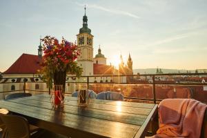 een tafel met bloemen op een balkon met een klokkentoren bij Residence Rybna 9- Old Town in Praag