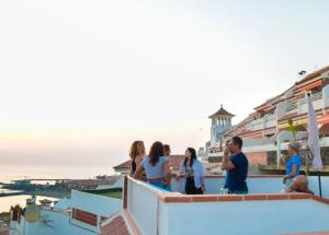 Grupa ludzi stoi na dachu i patrzy na ocean w obiekcie Banana Surf House w mieście Los Cristianos