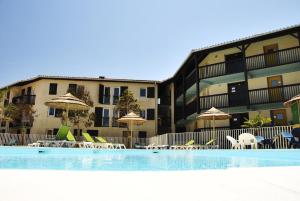 ein Hotel mit einem Pool mit Stühlen und Sonnenschirmen in der Unterkunft Village Vacances Le Junka in Vieux-Boucau-les-Bains