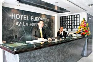 two men are sitting at a hotel reception desk at Hotel Ejecutivo Av la Esperanza in Bogotá