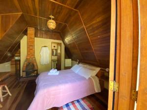 a bed in a room with a wooden ceiling at Pousada Cabanas do Visconde in Visconde De Maua