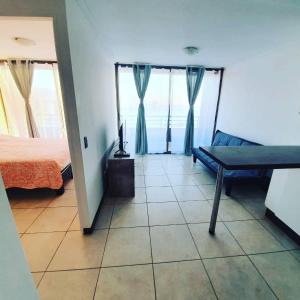 a bedroom with a bed and a couch and window at Departamento NEO IQUIQUE VISTA AL MAR 3 in Iquique