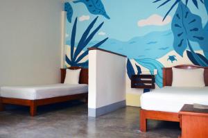 a room with two beds and a painting on the wall at Casa Losodeli & Coworking- Adults Only in Puerto Escondido