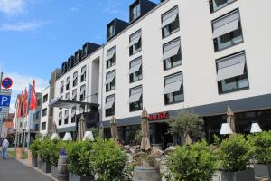 ein Gebäude mit Sonnenschirmen und Pflanzen davor in der Unterkunft Hotel Schweizer Hof in Kassel