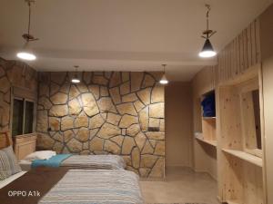 a bedroom with two beds and a stone wall at Le Gite du Barrage in Zaouia Ben Smine