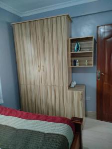 a bedroom with a bed and a wooden cabinet at Alken Homes - Two Bedroomed, Naivasha in Naivasha