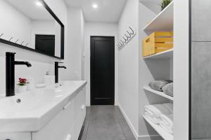 a white bathroom with a sink and a black door at Les Appartements du 300 in Quebec City
