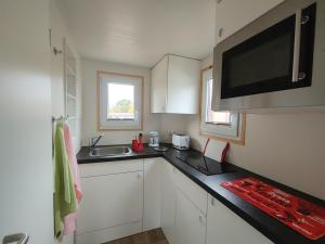 a small kitchen with white cabinets and a black counter top at MY LITTLE TINY HOUSE in Visselhövede