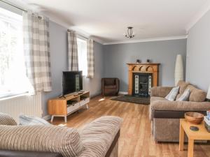 uma sala de estar com um sofá e uma televisão em Ivy Cottage em Colchester