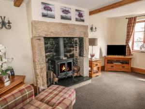 a living room with a fireplace and a tv at Post Office Cottage in Endon