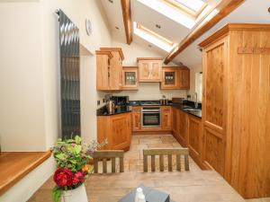 a kitchen with wooden cabinets and a table with a vase of flowers at Post Office Cottage in Endon