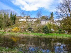 a building on a hill next to a body of water at River Cottage in Bakewell