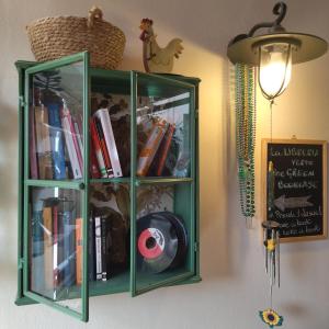 a green book shelf on a wall with books at Contus Rétro Guest House in Cagliari