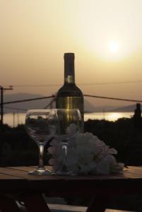 a bottle of wine and a glass and flowers on a table at Sunset Studios in Nea Stira