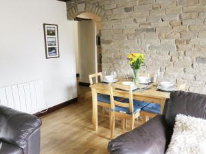 ein Esszimmer mit einem Tisch und einer Ziegelwand in der Unterkunft Hope Cottage in Leyburn