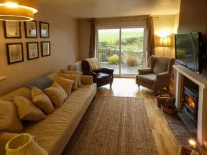 a living room with a large couch and a fireplace at Bridleway Cottage in Wennington