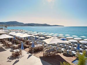 a beach with tables and chairs and umbrellas at Radisson Blu Hotel Nice in Nice