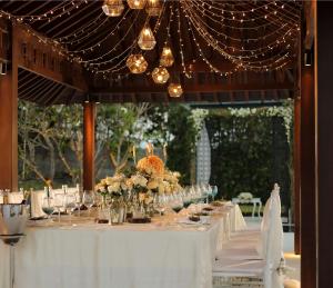 a table with a white tablecloth and flowers and lights at Radisson Blu Bali Uluwatu in Uluwatu