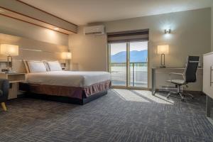 a hotel room with a bed and a desk and a window at Quality Inn Sunshine Suites in Terrace +189 photos