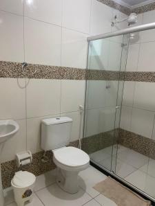 a bathroom with a toilet and a glass shower at Casa no Condomínio Vilas do Jacuípe in Camaçari