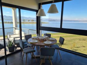 a dining room with a table and chairs and a view of the water at Dpto The View, Puerto del Águila Lago Los Molinos in Potrero de Garay
