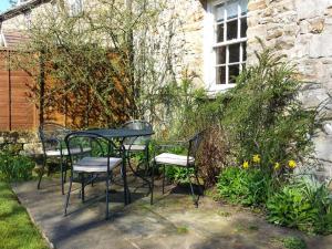 a table and chairs in a garden with a building at Farrier's Cottage in Sedbergh