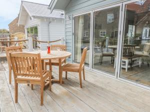 a wooden table and chairs on a screened in porch at Beach Walk in Reighton