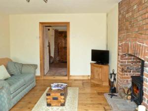 a living room with a couch and a brick fireplace at 3 Apsley Cottages in Chartham