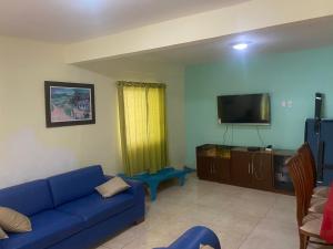 a living room with a blue couch and a tv at Casa no Condomínio Vilas do Jacuípe in Camaçari