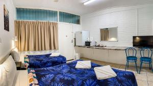 Habitación con 2 camas azules y barra. en Maryborough City Motel en Maryborough